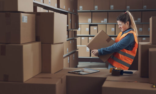 Female warehouse worker lifiting a heavy box