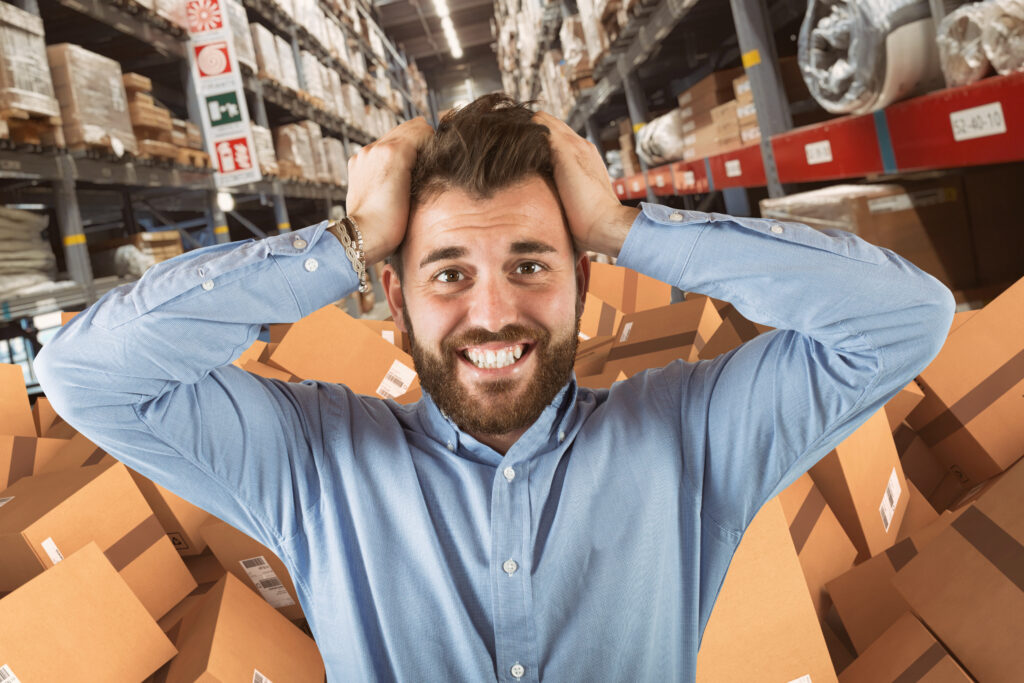 stressed out warehouse worker with a bunch of packages behind him