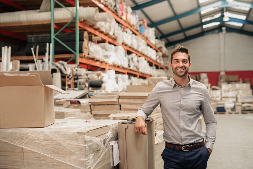 Smiling warehouse manager standing by pallet