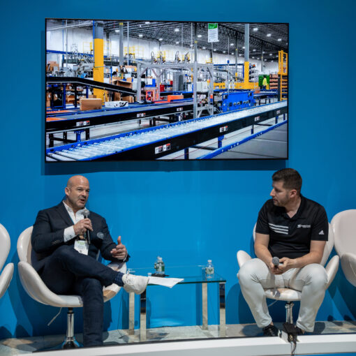 Two men talking on stage at a trade show about warehouse automation
