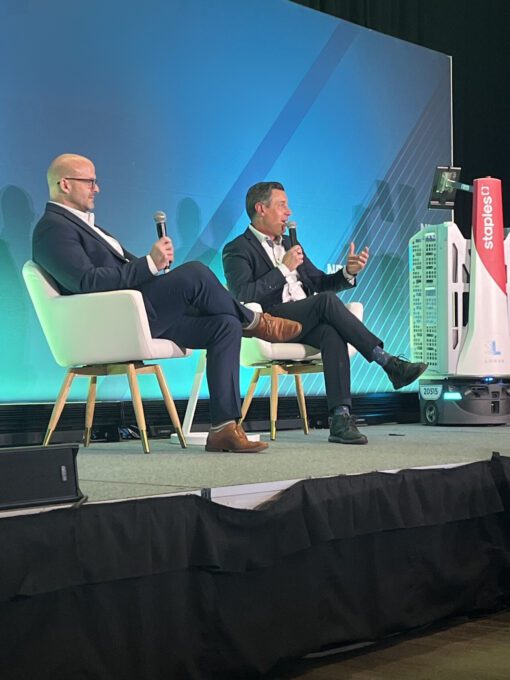 Two men on stage at a conference with a Locus Origin robot