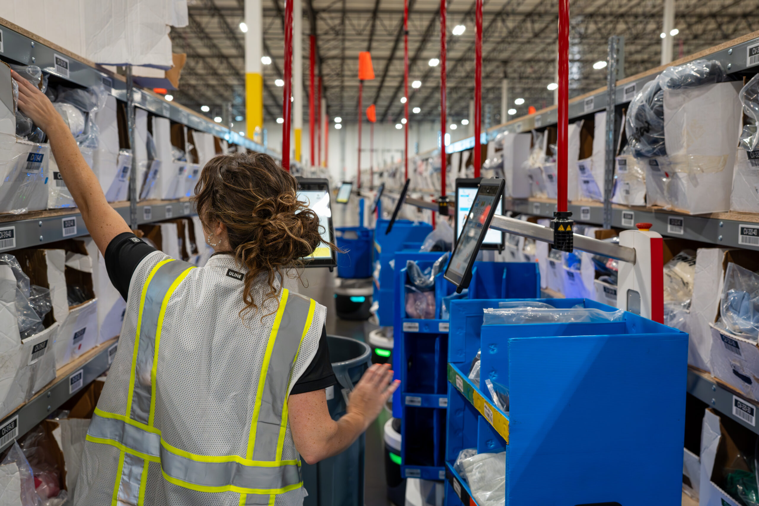 Woman picking in aisle of warehouse
