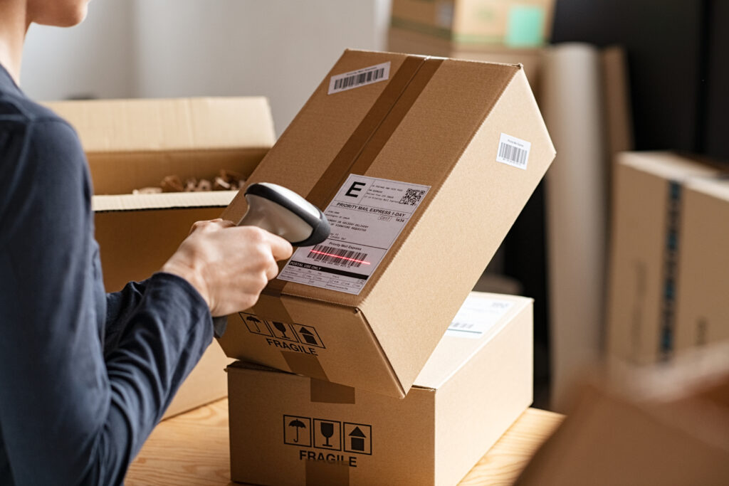 Worker scanning a shipping label on a cardboard parcel with a handheld barcode scanner