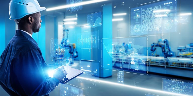 Engineer in a hard hat viewing holographic data screens overlaid on an automated robotic production line