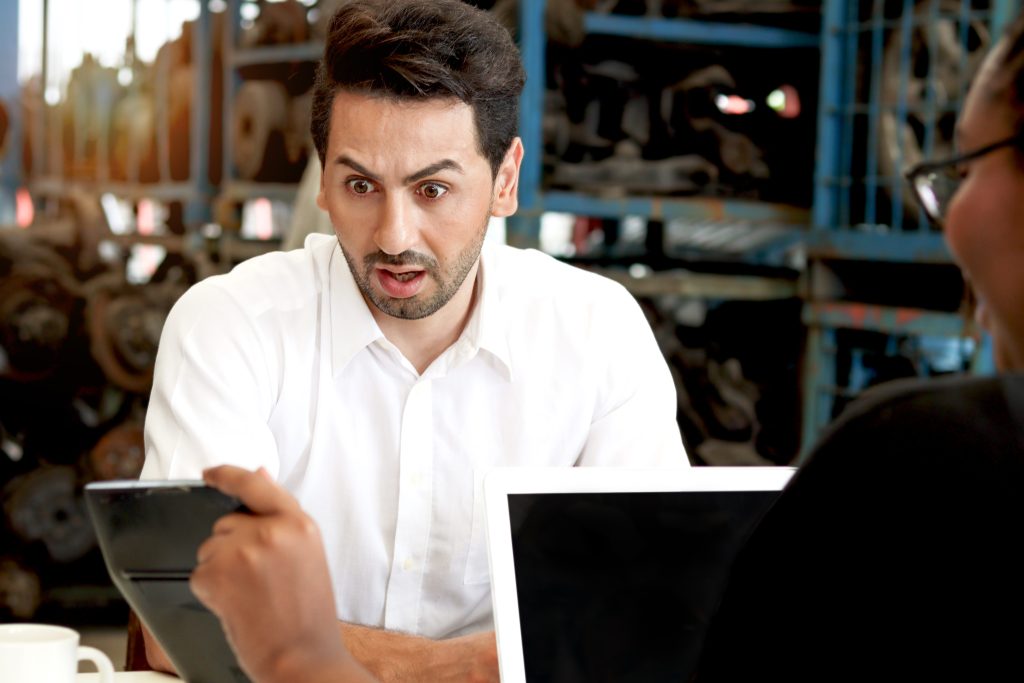 Surprised businessperson reacting to figures shown on a tablet during a meeting