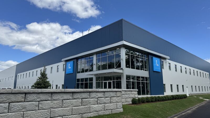 Locus Robotics headquarters building with blue Locus logo signs under a blue sky