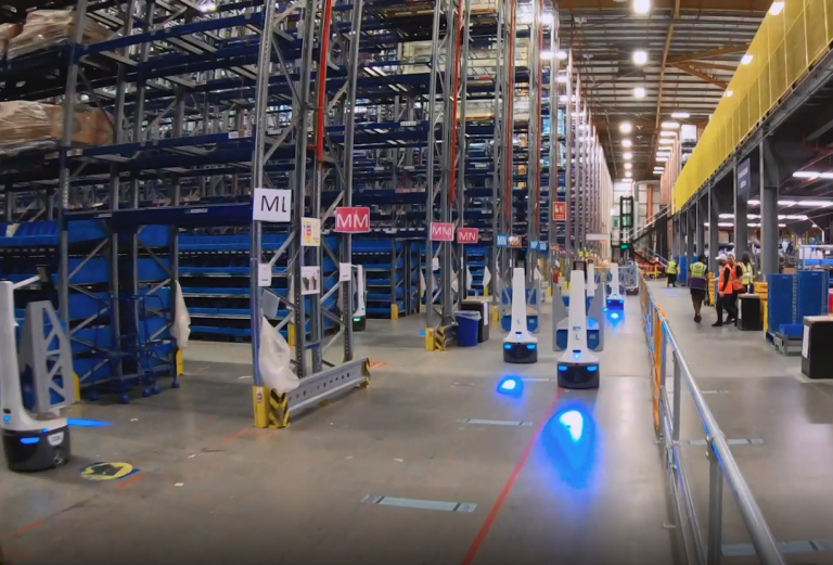 LocusBots projecting blue floor lights while traveling aisles between tall blue storage racks