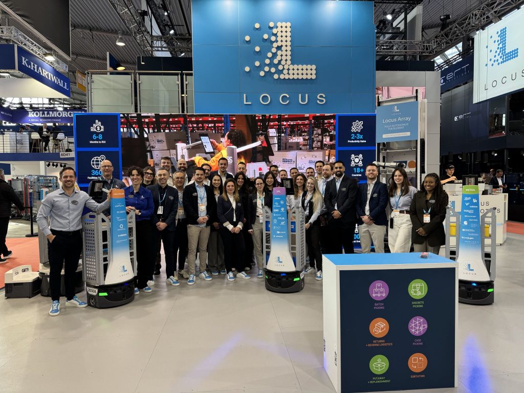 Locus Robotics team members posing with branded LocusBots at the Locus booth at LogiMAT 2026