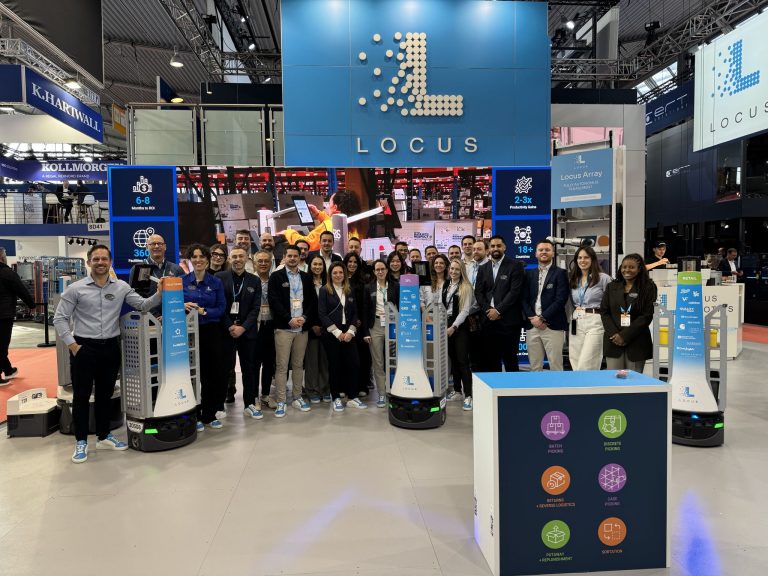 Locus Robotics team members posing with branded LocusBots at the Locus booth at LogiMAT 2026