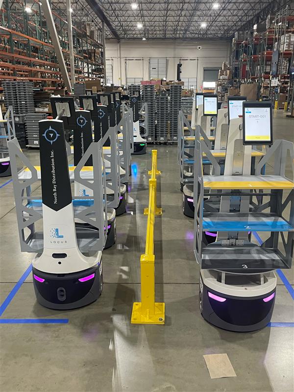 Rows of North Bay Distribution-branded LocusBots with touchscreens lined up on a warehouse floor