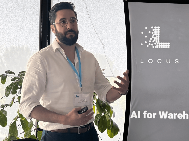 Oscar Mendez presenting at an event beside a Locus banner reading AI for Warehouses
