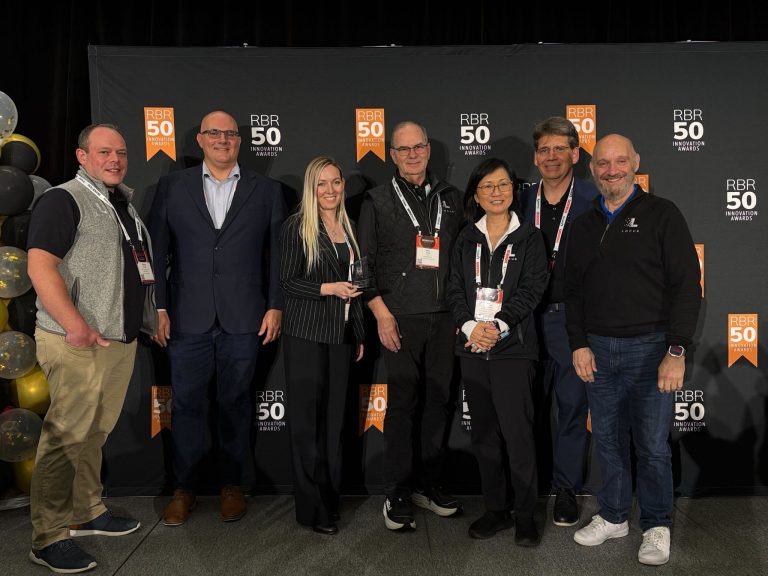 Group of eight people posing at the RBR50 Innovation Awards with an award trophy