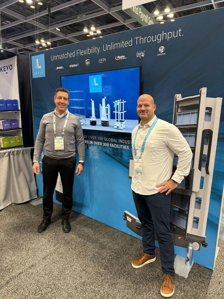 Two Locus Robotics representatives standing at the Locus booth at the NRF trade show