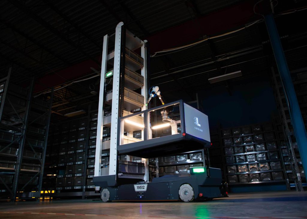 Locus Array robot with a vertical tote tower and robotic picking arm in a dark warehouse