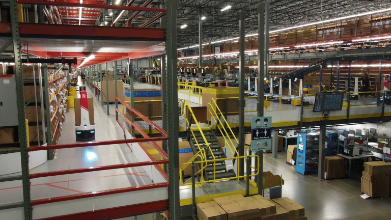 Radial warehouse mezzanine with yellow stairs, pick shelving and a LocusBot traveling an upper aisle