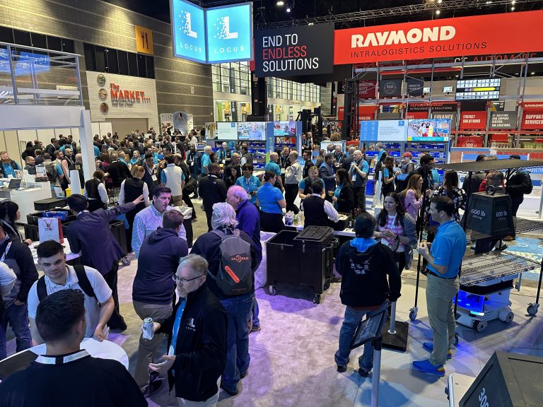 Crowd of trade show attendees mingling at a happy hour at the Locus Robotics booth
