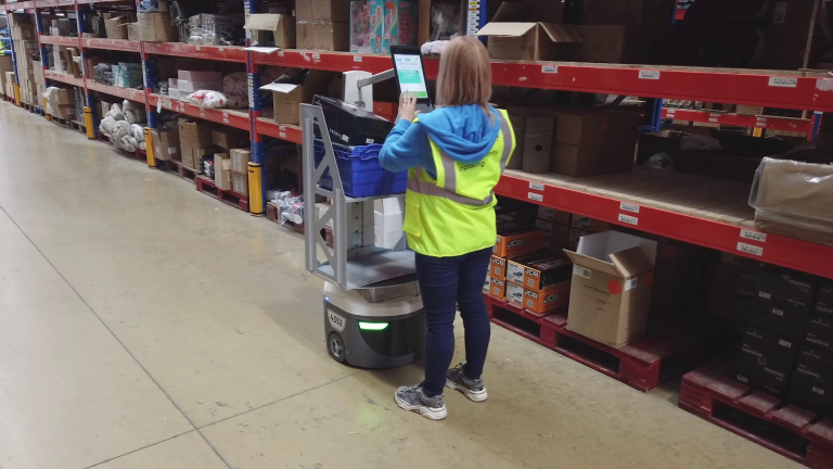Warehouse associate in a high-visibility vest using a LocusBot touchscreen while picking from shelving